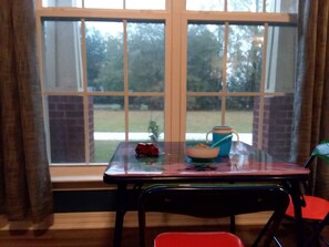 A room with a window, a table with a bowl and a toy car, and a chair.