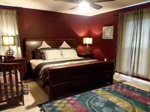 A bedroom with a bed, bedside lamps, a clock, and a window with curtains. - The "Home Over the Bridge" (Atmore)