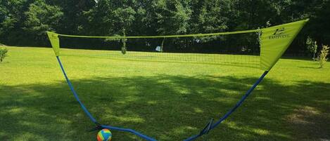 A badminton court with a net, a shuttlecock, and a racket.