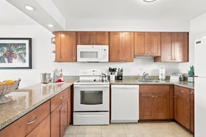 A modern kitchen with wooden cabinets, a microwave, an oven, and a dishwasher.