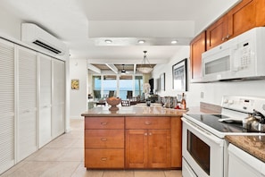 A modern kitchen with wooden cabinets, a built-in microwave, and a large island with a sink.