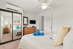 A bedroom with a bed, a dresser, a television, a ceiling fan, and a large mirror. - Oceanfront 2BR | Two Lanais, Turtles & Sunsets (Lahaina)