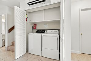 A laundry room with two stacked washers and dryers, a white door, and a vent above the dryers.