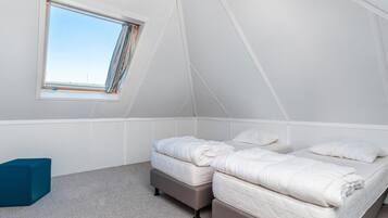 A bedroom with two beds, a window, and a blue chair.