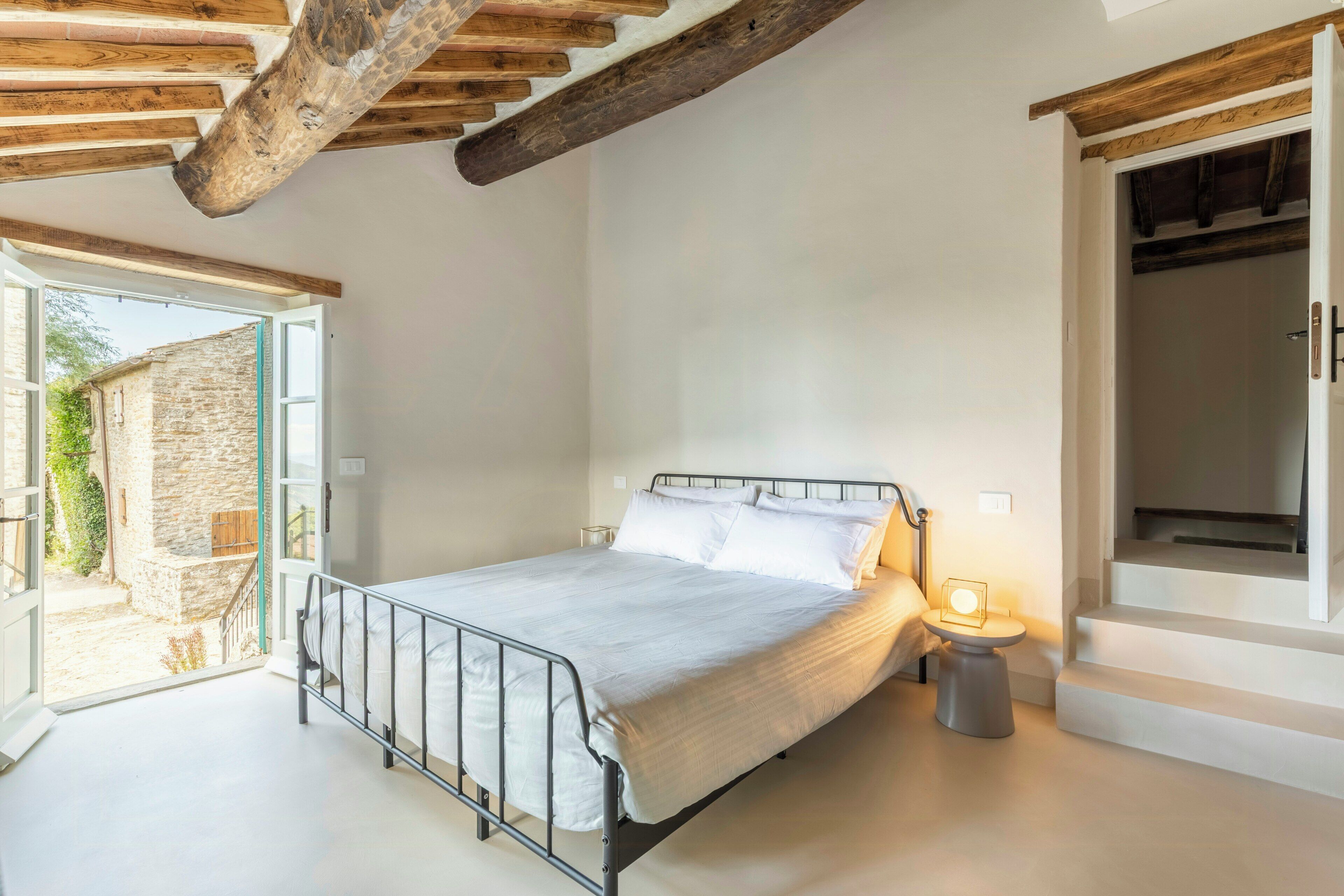 Un dormitorio con cama, mesita de noche y vistas al exterior.