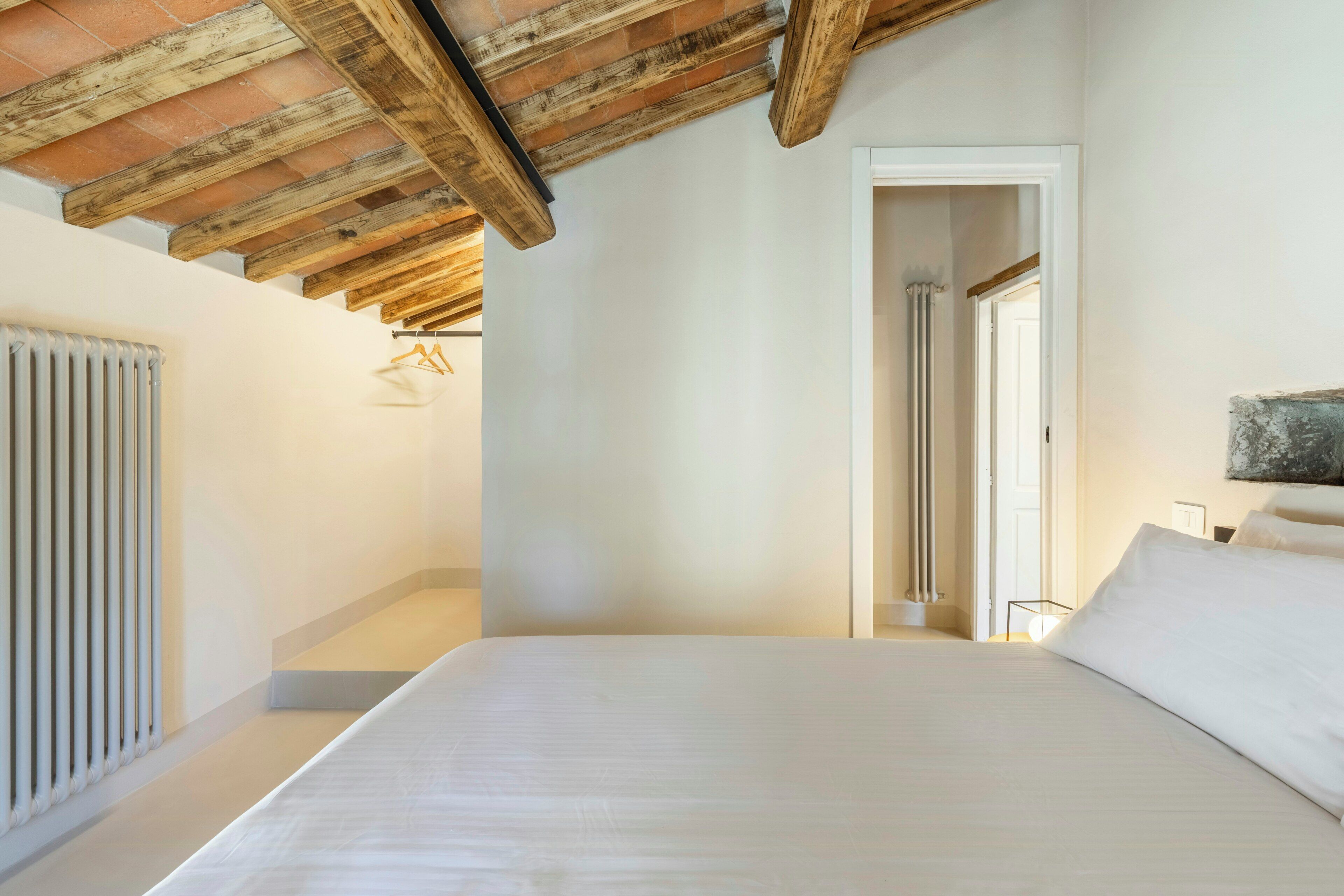 Une chambre à coucher avec un lit, un radiateur et un plafond en bois.