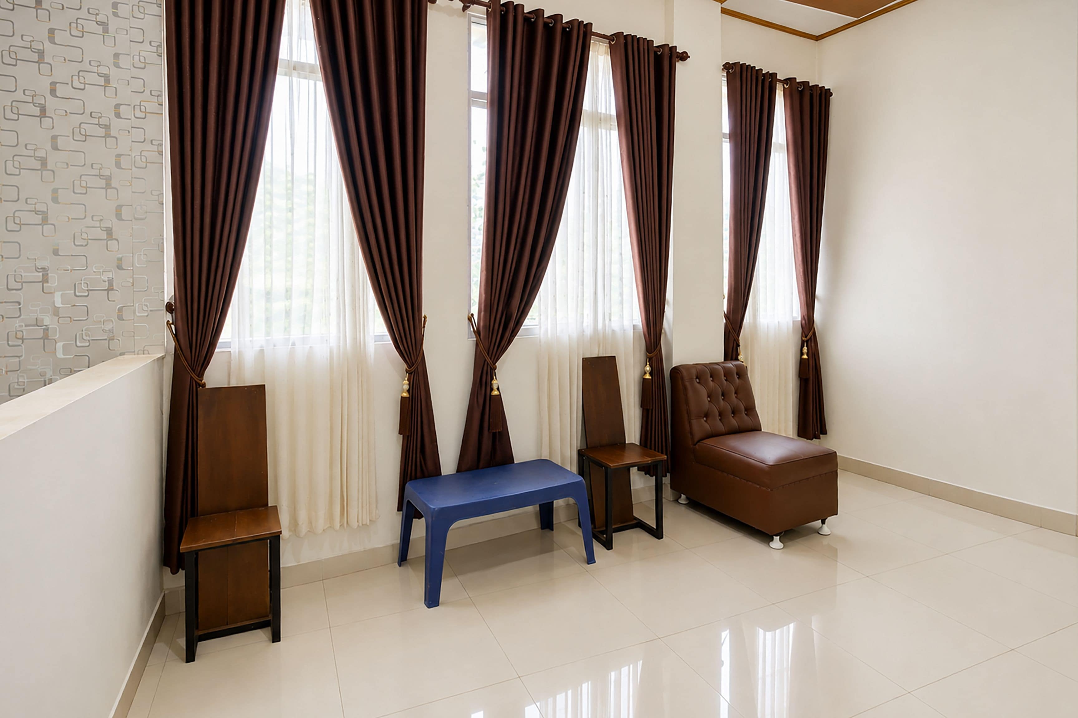 A room with a brown leather sofa, a blue bench, and two wooden chairs.