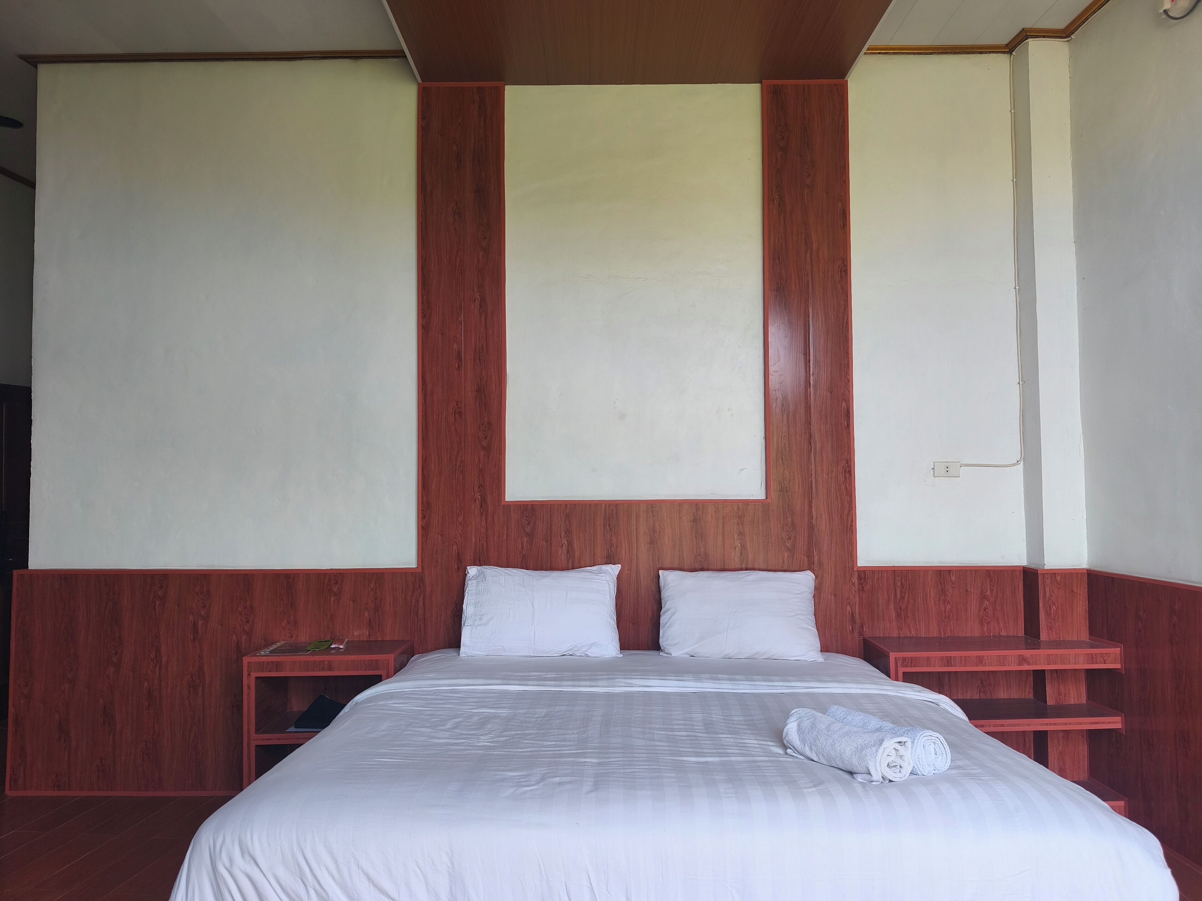 Una habitación de hotel con una cama grande, dos mesitas de noche y un cabecero de madera.