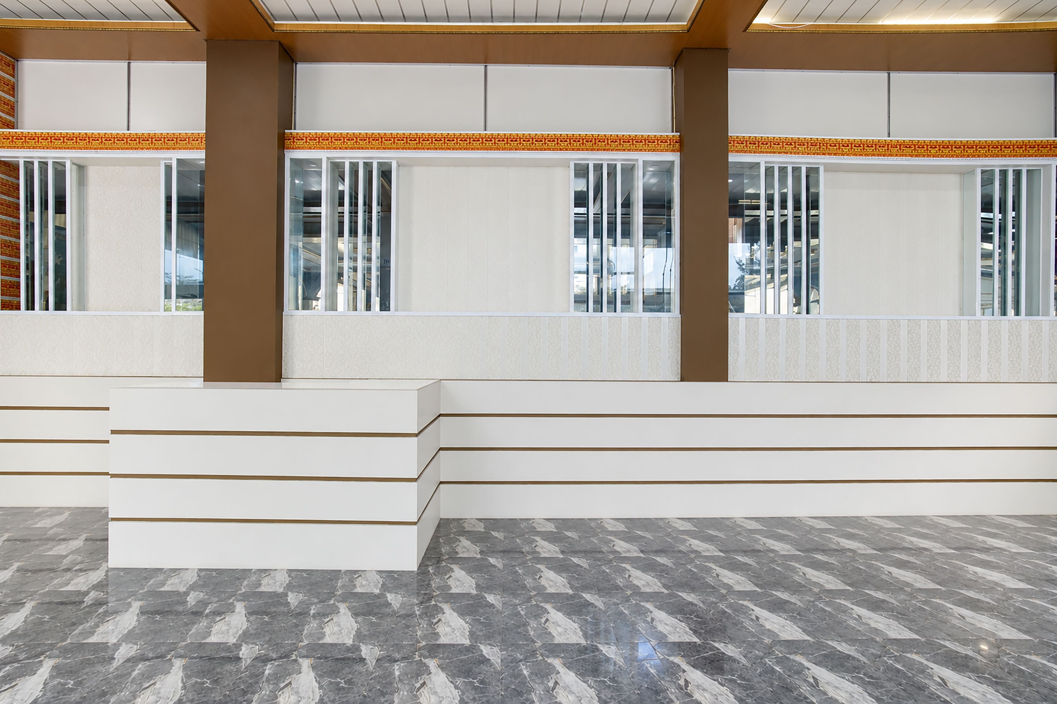 A spacious interior with a marble floor, white benches, and large windows with vertical blinds.