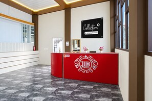 Un mostrador de recepción con un logotipo, un cartel arriba y una ventana a la derecha.