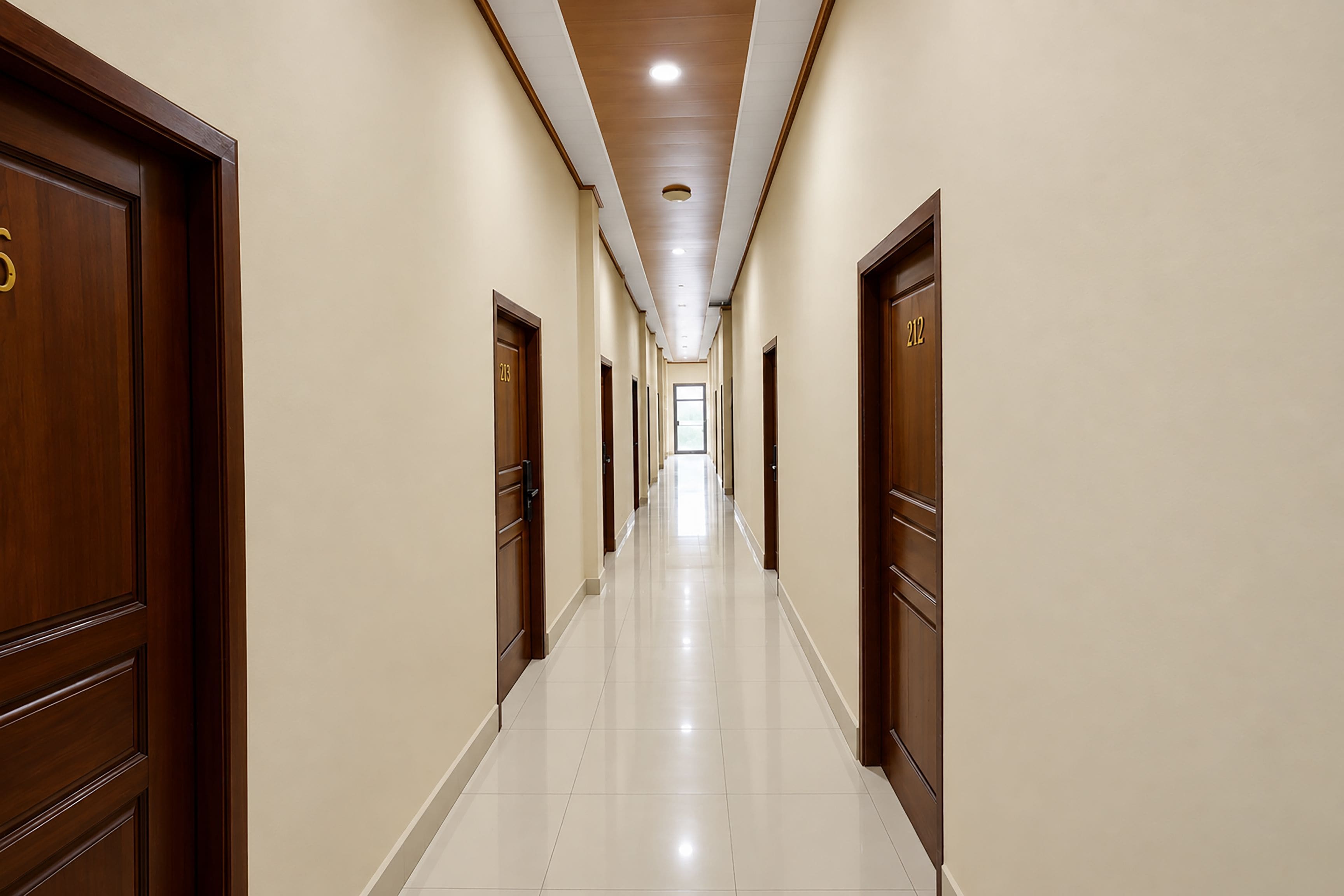 A hotel hallway with wooden doors, white tiled floors, and a ceiling with recessed lighting.