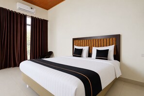 Una habitación de hotel con una cama grande, un cabecero estampado con rayas y un ventanal con cortinas.