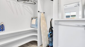 A clean, modern bathroom with a shower, a mirror, and a vacuum cleaner.
