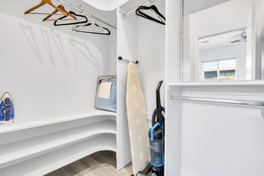 A clean, modern bathroom with a shower, a mirror, and a vacuum cleaner.