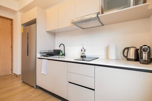 Eine moderne Küche mit eingebauter Mikrowelle, Wasserkocher und Kaffeemaschine auf der Arbeitsfläche.