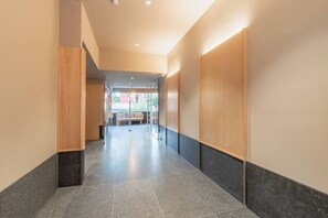 A modern hallway with a bench, wooden paneling, and recessed lighting. - Myla - 1BR Apartment Near Centro Historico (Mexico City)