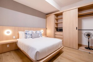 Ein modernes Schlafzimmer mit Bett, Nachttischen, einem Kleiderschrank und einem Standventilator.