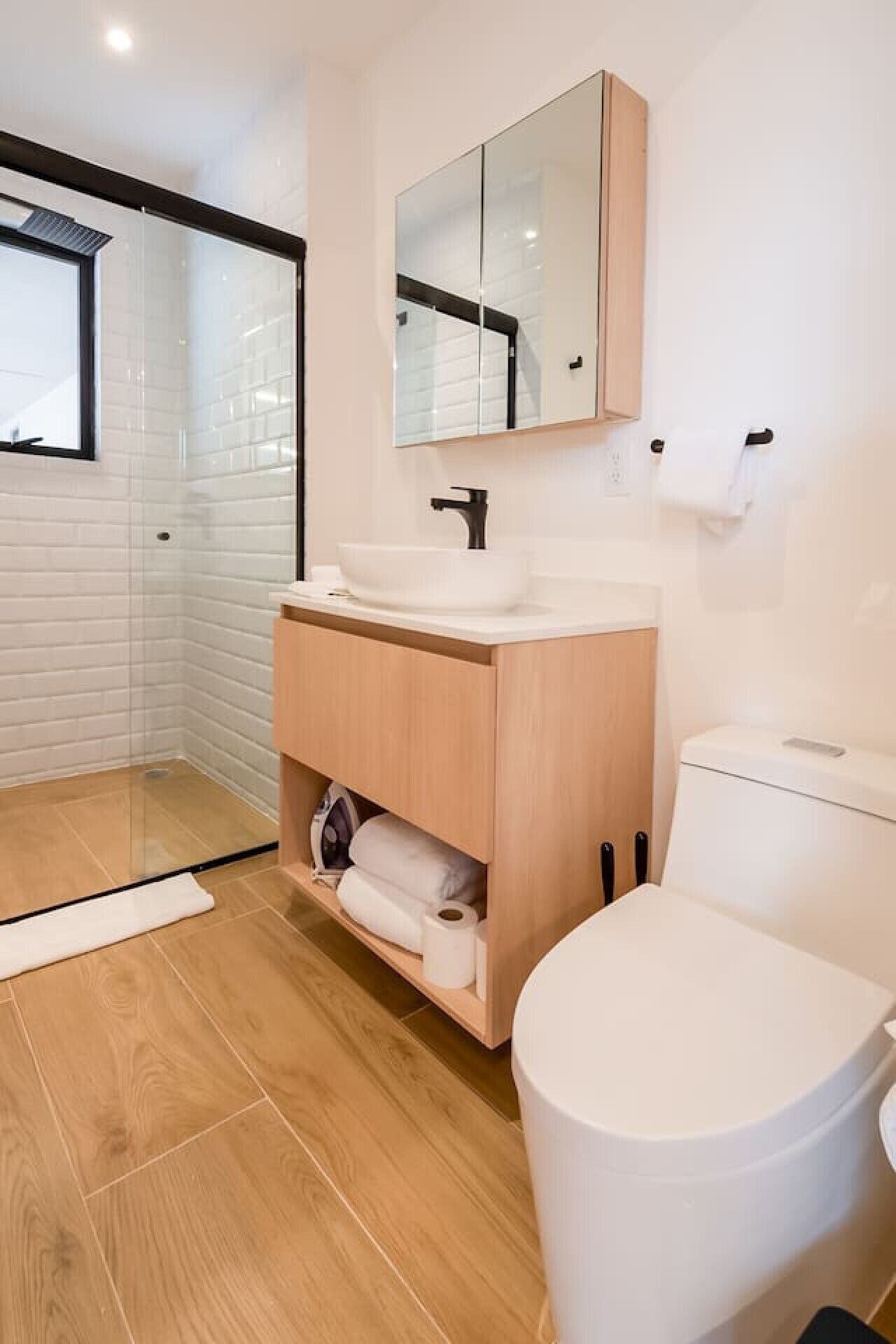 Une salle de bain moderne avec une douche à parois de verre, un meuble-lavabo en bois et des toilettes.