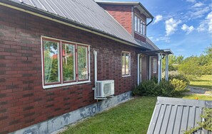 Ein rotes Backsteinhaus mit grauem Dach, großen Fenstern und einer Klimaanlage.