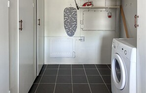 Une buanderie équipée d’un lave-linge, d’un radiateur et d’un fer à repasser suspendu.