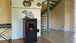 A room with a wood-burning stove, a keyboard, and decorative fish on the wall. - 3 bedroom gorgeous home in Hemse (Hemse)