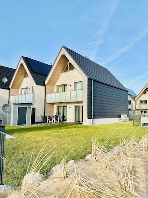 Ein modernes Wohngebäude mit Satteldach, Solaranlage und gepflegtem Rasen.