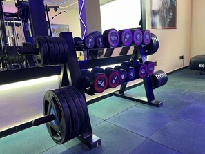 Um banco de musculação com halteres ajustáveis e barra.