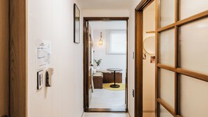 Un pasillo con una puerta de madera a la izquierda, un aplique en la pared y un ventanal corredizo a la derecha.