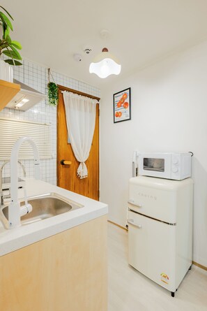 A kitchen with a sink, a microwave, and a wooden door with a white curtain. - DEN: 2 mins walk to Hapjeong Station / 10-minute walk to Hongdae Street (Seoul)