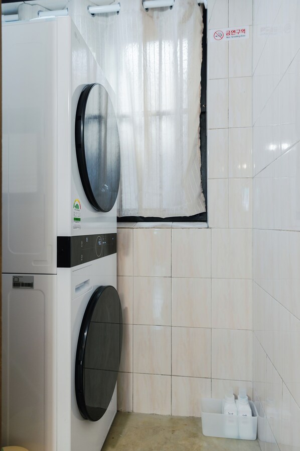 A laundry area with a washing machine, a dryer, and a small storage bin with bottles.