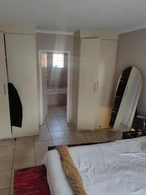 A bedroom with a bed, wardrobe, and a mirror.