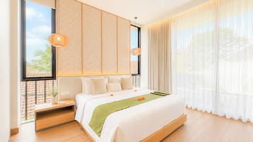 A modern hotel room with a large bed, a bedside table, a window with a view, and a hanging light fixture.