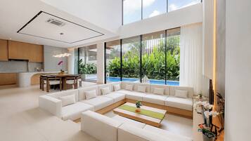 A modern living room with a sectional sofa, a dining area, and a view of a swimming pool.