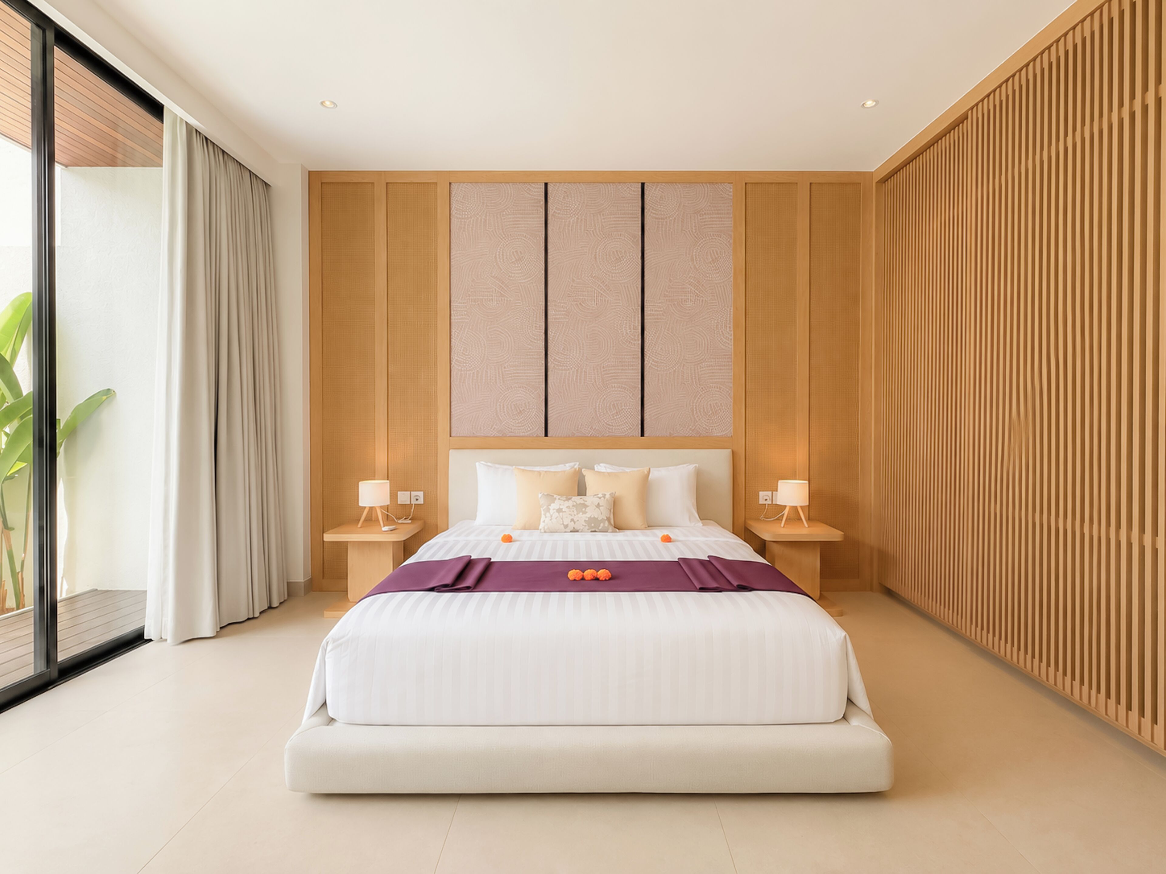 A modern hotel room with a large bed, two bedside tables, a wall with vertical wooden slats, and a large window with curtains.