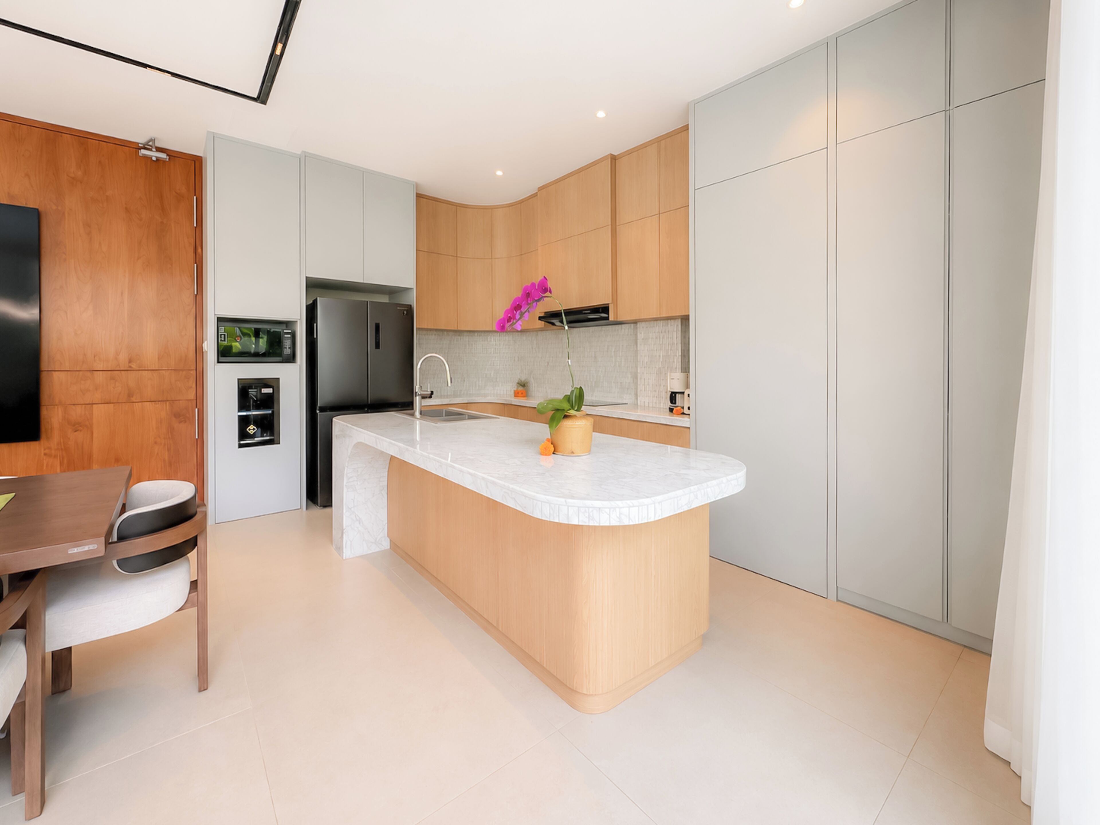 A modern kitchen with a central island, wooden cabinets, and a built-in refrigerator.