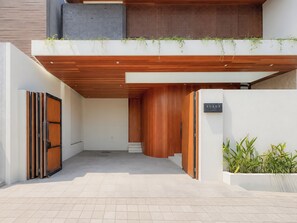 A modern building entrance with a wooden facade, a sign reading 'ALAYA,' and a planter with greenery. - Alaya Villa Seminyak by Nagisa Bali (Badung)