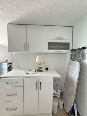 A compact kitchenette with a microwave, a small table with a lamp, a washing machine, and a drying rack. - Superb 3-bedroom house with AC in charming Kaş (Kaş)