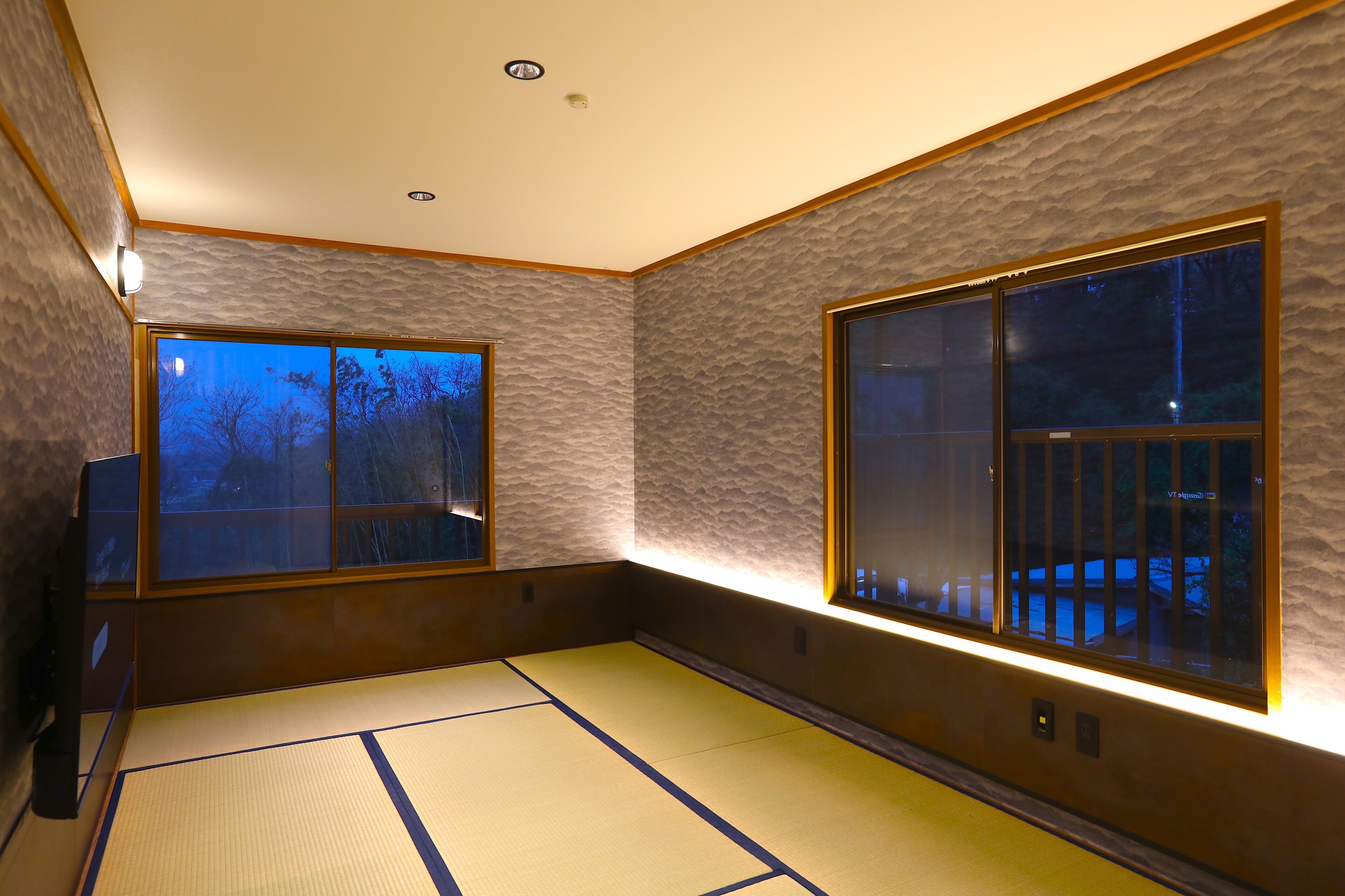 Ein traditioneller Raum mit Tatami-Matten, zwei großen Fenstern und einer Wandleuchte.