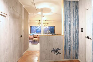A modern interior with a wooden floor, a central island with a turtle decal, and a view of a dining area with a large window. - Keshiki Nakamura | 1 hour from Tokyo · Ocean View (富津市)