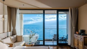 A hotel room with a large sliding glass door leading to a balcony with a view of the sea. - View of the Sea Vatican (Dali City)