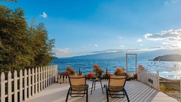 A deck with two chairs and a table, overlooking a body of water with a clear sky. - View of the Sea Vatican (Dali City)