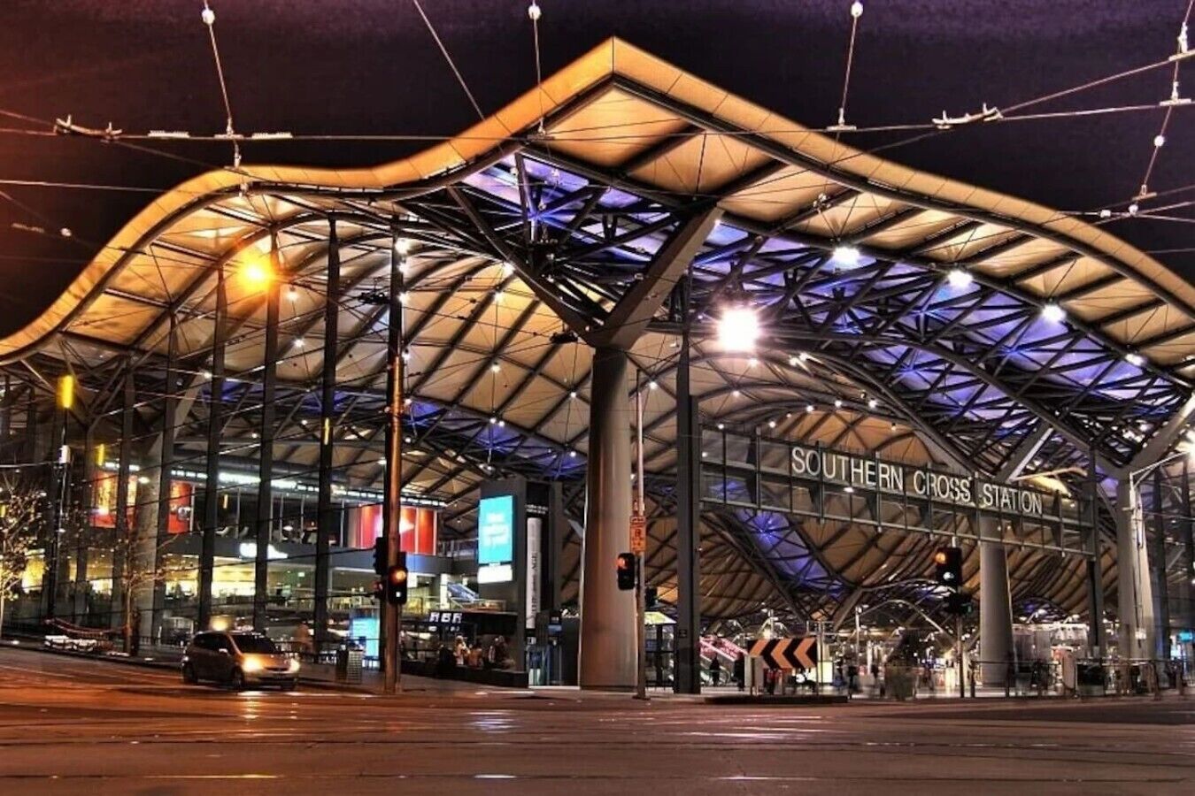 Ein modernes Gebäude mit einer großen, gewölbten Dachkonstruktion und einem Schild mit der Aufschrift 'SOUTHERN CROSS STATION'.