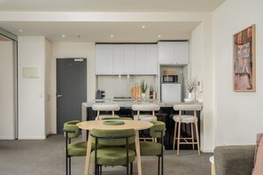 A modern kitchen with white cabinets, a central island, and bar stools. - Downtown Stylish Apartment w/ Pool, Gym & Parking! (West Melbourne)