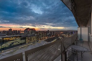 A cityscape view from a balcony with a metal railing and a table. - Downtown Stylish Apartment w/ Pool, Gym & Parking! (West Melbourne)