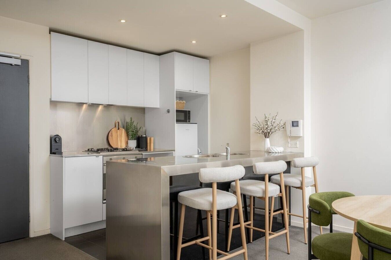 Une cuisine moderne dotée d’un îlot central, de tabourets de bar et d’une table à manger.