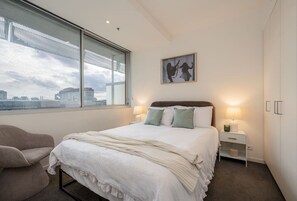 Bedroom 1 – Bright and comfortable bedroom with a cosy bed, built-in wardrobe and large window offering city views. - Downtown Stylish Apartment w/ Pool, Gym & Parking! (West Melbourne)