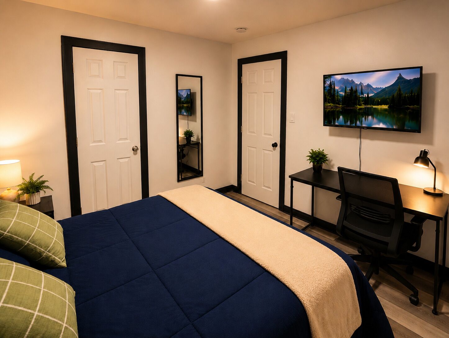 Ein Schlafzimmer mit Bett, Schreibtisch, Stuhl, Fernseher und Spiegel.