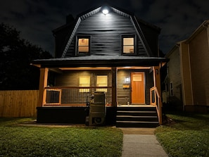 A two-story house with a front porch, a visible mailbox, and a number '990' on the side.