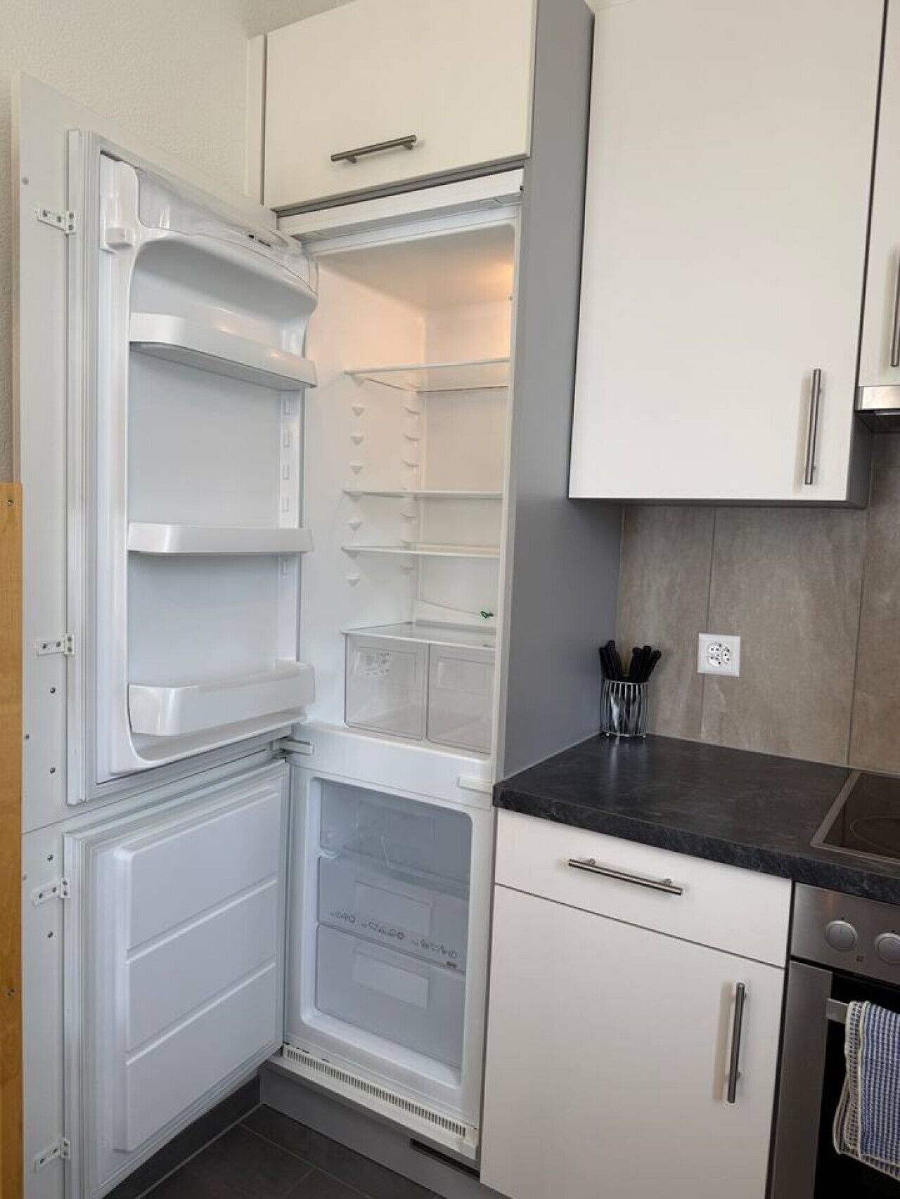Une cuisine équipée d’un réfrigérateur encastré, d’un plan de travail et de placards.