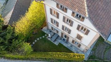 Ein mehrstöckiges Gebäude mit Innenhof, gepflasterter Terrasse und einer Hecke.